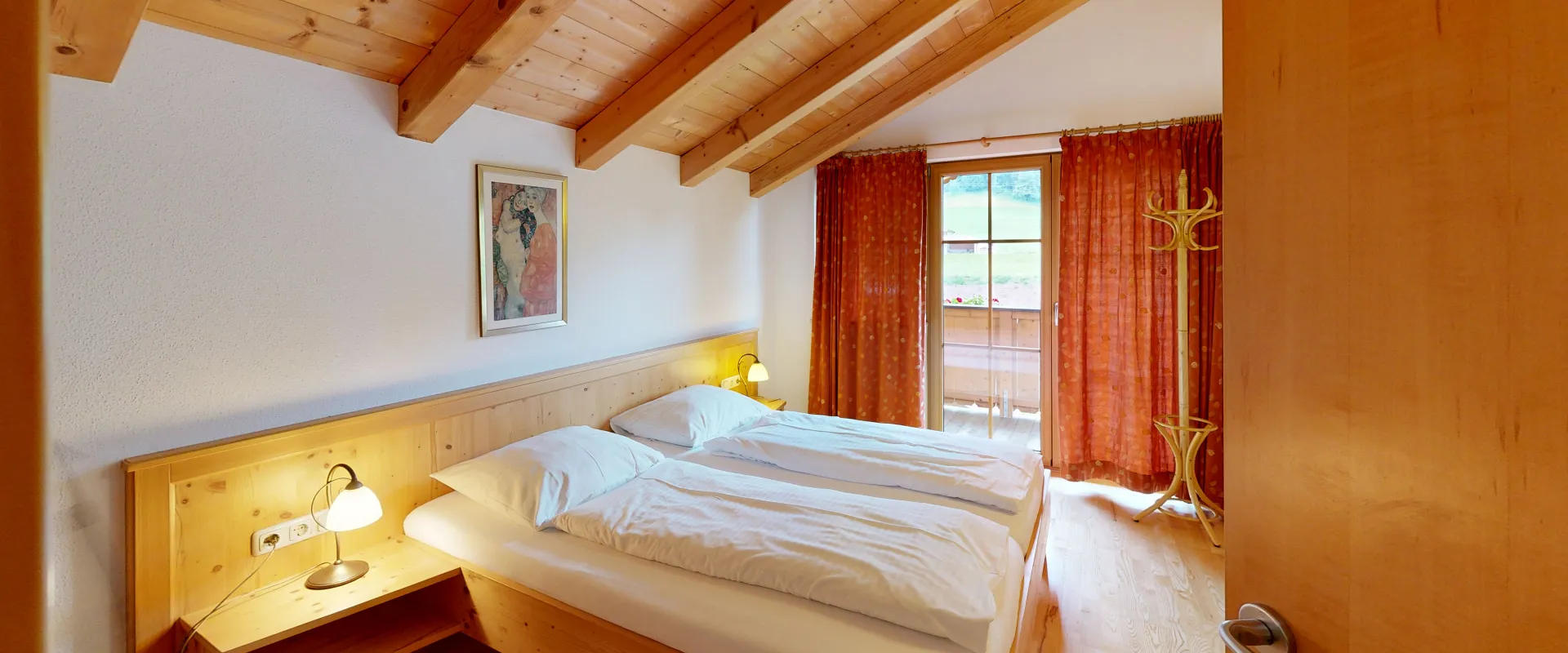 Helles Schlafzimmer mit Dachschrägen, zwei Betten und Fenster mit Vorhängen.